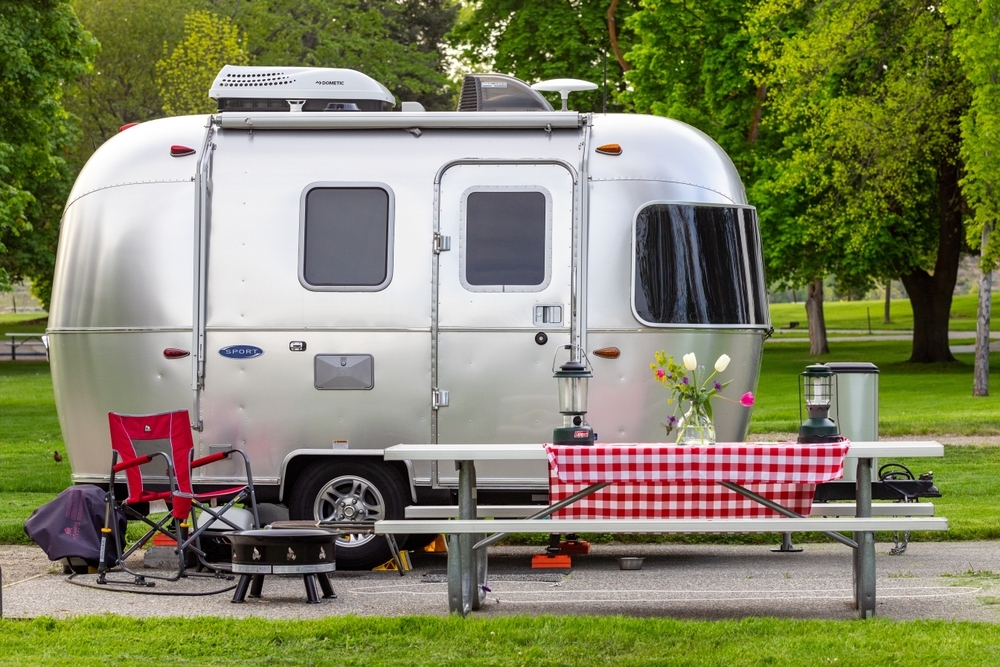 small Airstream camper at campsite with picnic table